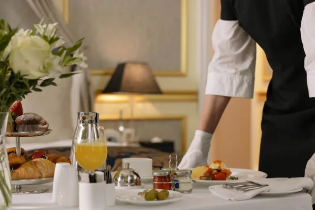 A waiter setting down a plate at a laid breakfast table in a hotel room