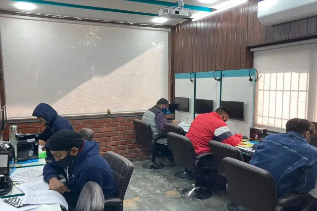 Students working through practice papers at their desks, with the projector screen down at the front of the room.